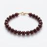 A studio product shot of a women's 8mm natural garnet bead bracelet with a 14k gold-filled lobster clasp. 