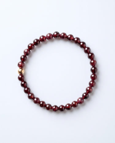 A studio product shot of a women's 6mm garnet bead bracelet featuring a single 14K gold-filled accent bead on a white background.