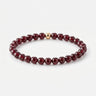 A studio product shot of a women's 6mm garnet bead bracelet featuring a single 14K gold-filled accent bead.