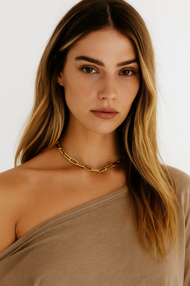 A lifestyle shot of a model wearing the Gold Chunky Chain necklace against a neutral-toned top, demonstrating its versatile, high-end silhouette.
