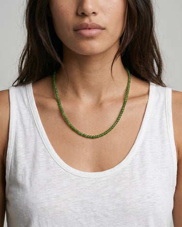 Woman wearing a green jade beaded necklace against a neutral background
