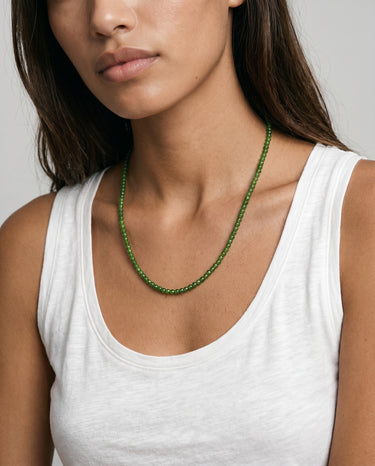 woman with a white tank top wearing 4mm round green jade beaded necklace against a plain background