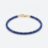 A studio product shot of a women's 2-3mm natural faceted lapis lazuli cube bead bracelet with a sterling silver lobster clasp, highlighting the deep royal blue gemstone tones and light-catching geometric facets.