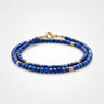 A studio product shot of a women's 3mm natural faceted lapis lazuli cube wrap bracelet featuring 14K gold-filled bead accents, highlighting the vibrant royal blue gemstones and elegant layered design.