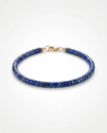 A studio product shot of a women's 4mm natural lapis lazuli heishi bead bracelet with a 14K gold-filled clasp, highlighting the deep royal blue gemstone tones and sleek disk shape.