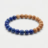 A studio product shot of an 8mm natural lapis lazuli and golden sandalwood bead bracelet, highlighting the contrast between the deep royal blue gemstones and the warm, matte wood texture.