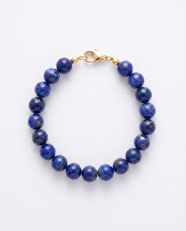 A studio shot of a women's 8mm natural lapis lazuli bead bracelet with a 14K gold-filled lobster clasp, highlighting the deep royal blue gemstone tones and high-polish finish.