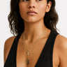 A lifestyle shot of a model wearing a layered set of 18" and 20" 14K gold-filled box chains with handmade freeform pendants against a black top.
