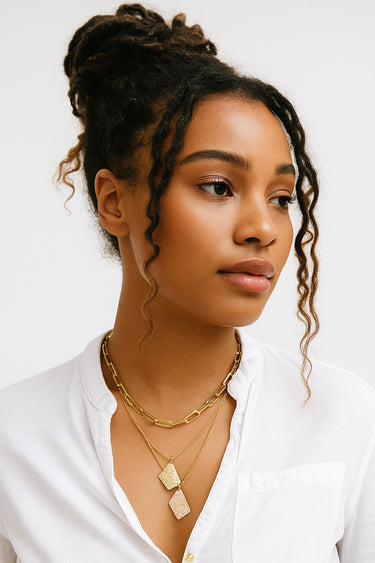 A lifestyle shot of a model wearing the 14K gold-filled freeform pendants layered with a chunky chain against a white collared shirt.
