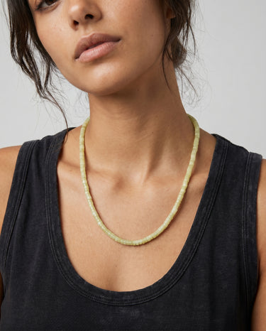 Woman wearing a 4x2mm lemon jade heishi bead necklace styled with a black tank top.