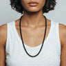 Woman wearing a matte black onyx bead necklace against a neutral background