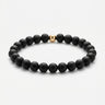 A studio product shot of a women's 6mm matte black onyx bead bracelet featuring a single 14K gold-filled accent bead.