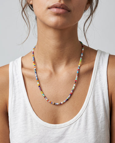 A woman wearing a 4mm millefiori round bead necklace, showcasing the vibrant colorful  glass beads against a white tank top.