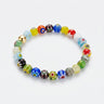 A studio product shot of a 8mm handmade Millefiori glass bead stretchy  bracelet featuring a 14K gold-filled accent bead, showcasing vibrant multi-colored floral patterns.