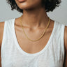 woman with a white tank top wearing 2mm faceted peridot beaded necklace against a plain background