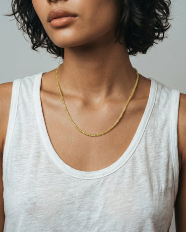 woman with a white tank top wearing 2mm faceted peridot beaded necklace against a plain background