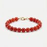 A studio product shot of a women's 8mm natural red agate bead bracelet with a 14K gold-filled lobster clasp, highlighting the vibrant crimson tones and high-polish finish.