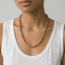 Woman wearing an 8mm sandalwood beaded necklace paired with a tank top on a light gray background. 