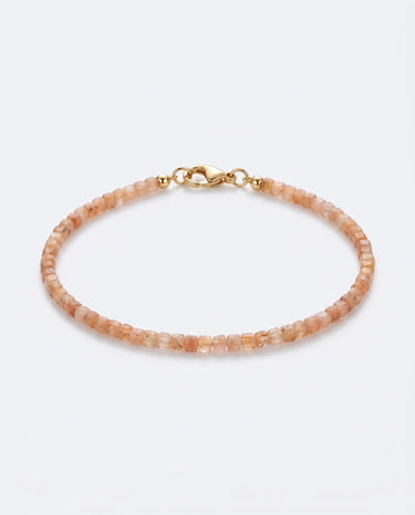 A studio product shot of a women's 2mm natural faceted golden sunstone cube bead bracelet with a 14K gold-filled clasp, highlighting the shimmering peach tones and delicate light-catching facets.
