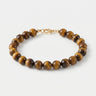 A studio product shot of a women's 8mm natural tiger's eye bead bracelet with a 14k gold-filled lobster clasp.