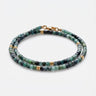 A studio product shot of a women's 3mm natural faceted tourmaline cube wrap bracelet featuring 14K gold-filled bead accents, highlighting the multi-tonal green gemstones and elegant layered design on a white background.