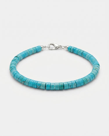 A studio product shot of a 4mm turquoise heishi bead bracelet with a sterling silver lobster clasp, showcasing the uniform disk shape and natural semi-precious stone texture.

