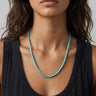 Close-up of a woman wearing a turquoise heishi beaded necklace against a neutral background