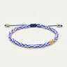 Studio product shot of a woman's adjustable vintage blue and white Afican chevron glass bracelet with gold accents, and sliding knot closure, and matching  dangles.