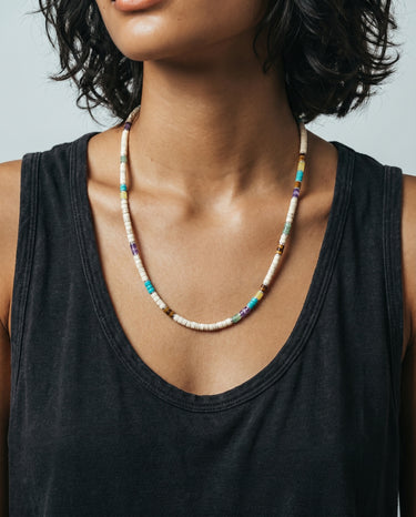 woman wiht a black tank top wearing a white turquoise heishi necklace with an assortment accent of heishi stones like tiger's eye, amethyst, aventurine, lemon jade, and blue turquois throughout the necklace.