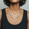 A studio shot of a female model wearing a colorful mixed heishi bead necklace against a neutral background