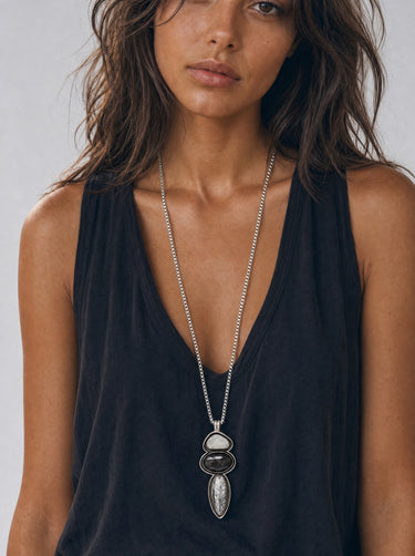 Woman wearing a sculptural Fossato sterling silver pendant featuring Gray Druzy Quartz, Silver Sheen Obsidian, and Picasso Jasper on a long silver chain.