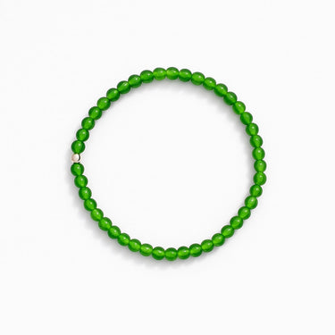 Product shot of a 4mm round green jade beaded stretchy bracelet with one 4mm round sterling silver-bead accent on a white background