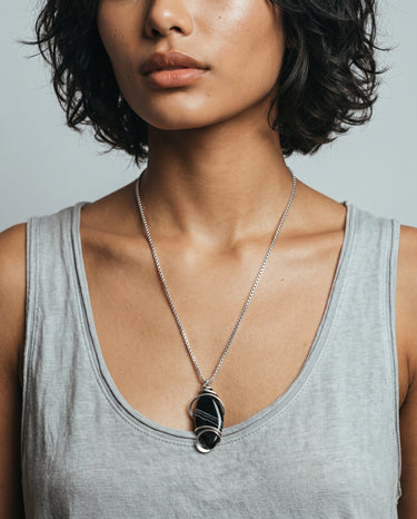 Close-up of a woman wearing a handcrafted Black Obsidian pendant featuring flowing sterling silver wirework and selectively hammered details.