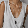 Woman wearing a long silver chain necklace with a polished Black Obsidian pendant, hand-wrapped in sculptural sterling silver wire.