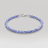 A beaded bracelet with alternating blue and white African chevron glass beads, finished with a silver lobster clasp, shown on a light gray background.