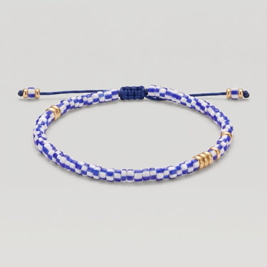 A beaded adjustable bracelet with a blue and white checkered pattern, accented with gold spacer beads, on a light gray background.