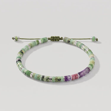 Studio product shot of adjustable chrysoprase heishi bracelet with sterling silver accents, amethyst and pink rhodonite beads, sliding knot closure, and  matching gemstone dangles.