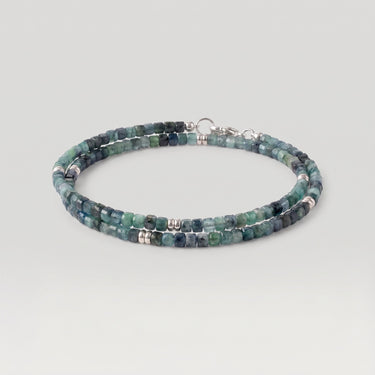 A double-strand beaded necklace made of faceted blue-green gemstone beads with silver spacer beads and a silver clasp, shown on a light gray background.