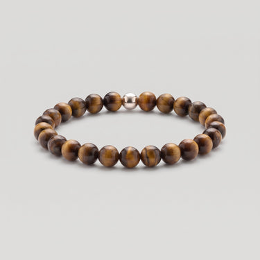 A studio product shot of a women's 6mm tiger's eye bead stretchy bracelet featuring a single sterling silver accent bead.