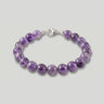 A studio product shot of a women's 8mm natural amethyst bead bracelet with a sterling silver lobster clasp on a light gray background.