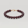 A studio product shot of a women's 8mm natural garnet bead bracelet with a 14k gold-filled lobster clasp. 