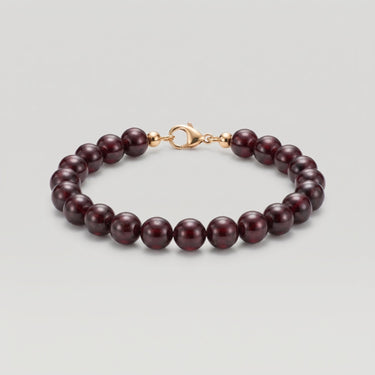 A studio product shot of a women's 8mm natural garnet bead bracelet with a 14k gold-filled lobster clasp. 