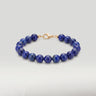 A product shot of a women's 8mm natural lapis lazuli gemstone bead bracelet with a 14K gold-filled lobster clasp, highlighting the deep royal blue tones.