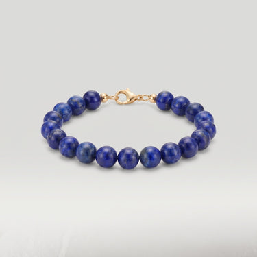 A product shot of a women's 8mm natural lapis lazuli gemstone bead bracelet with a 14K gold-filled lobster clasp, highlighting the deep royal blue tones.