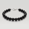 A studio product shot of a women's 8mm natural gloss onyx bead bracelet with a sterling silver lobster clasp on a light gray background.