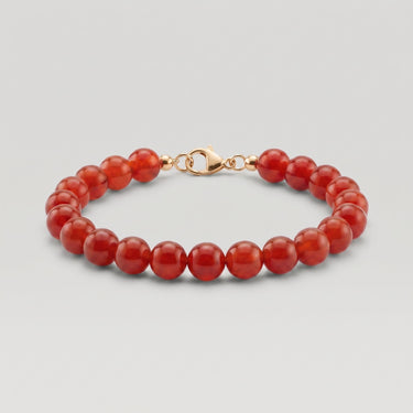 A studio product shot of a women's 8mm natural red agate bead bracelet with a 14K gold-filled lobster clasp, highlighting the vibrant crimson tones and high-polish finish.