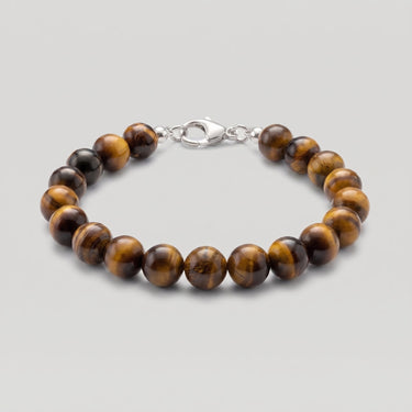 A beaded bracelet made of polished brown and black tiger's eye beads with a silver lobster clasp, shown on a neutral light gray background.