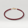 A studio hero shot of a women's 3mm natural faceted garnet cube bead bracelet with a 14K gold-filled clasp, highlighting the light-catching facets and deep wine-red gemstone tones.