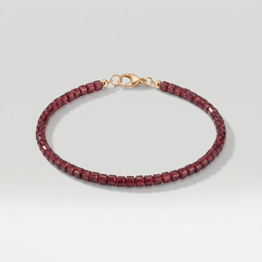 A studio hero shot of a women's 3mm natural faceted garnet cube bead bracelet with a 14K gold-filled clasp, highlighting the light-catching facets and deep wine-red gemstone tones.
