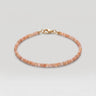 A studio product shot of a women's 2mm natural faceted golden sunstone cube bead bracelet with a 14K gold-filled clasp, highlighting the shimmering peach tones and delicate light-catching facets.
